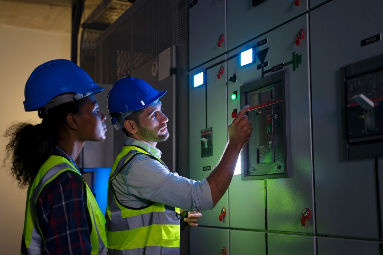 Dos técnicos con casco revisando un cuadro eléctrico